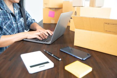 Küçük girişimciler ürünlerini paket kutulara yerleştirerek KOBİ işlerini evde başlatıyorlar. Fikir, sipariş almak ve sevkiyat yapmak için dizüstü bilgisayarlarla internet üzerinden satış yapmaya başlamak..