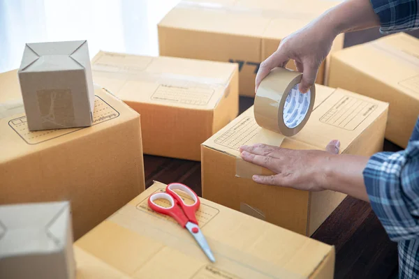 Closeup view of female online store small business owner seller entrepreneur packing package post shipping box preparing delivery parcel.