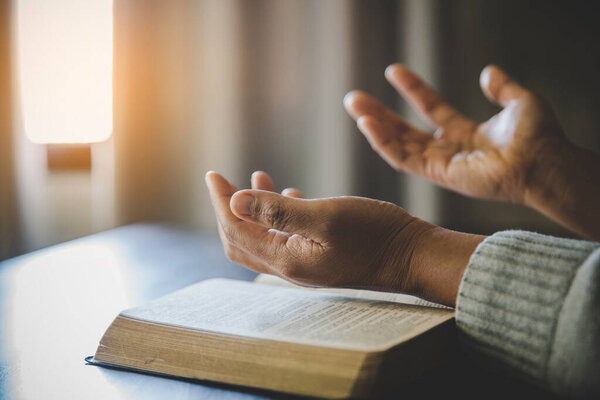a woman praying with hands on bible