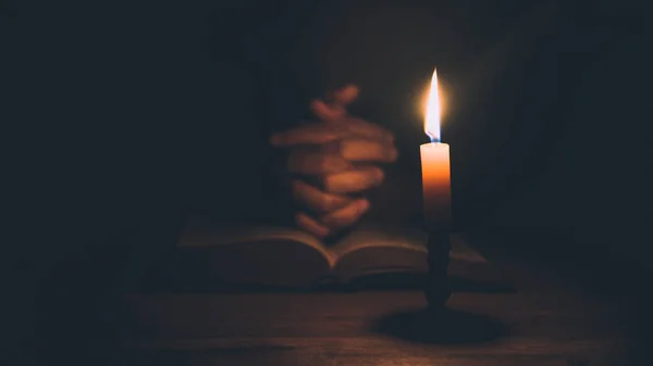 Woman hands praying on holy bible in the light candles selective focus. Beautiful gold background. Religion concept.