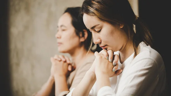 Two women praying worship believe. soft focus, praying and praise together at home. devotional or prayer meeting concept.