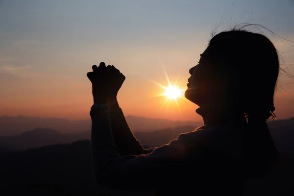 Silhouette woman on sunset background. Woman raising his hands in worship. Christian Religion concept background.