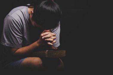 christian woman hand on holy bible are pray and worship for thank god in church with black background, adult female person are reading book, concept for faith, spirituality and religion