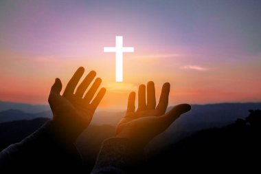 Silhouette of human hands palm up praying and worship of cross, eucharist therapy bless god helping, belief, forgiveness, freedom, hope and faith, christian religion concept on sunset background.