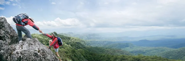 Person hike friends helping each other up mountain. Man and woman giving helping hand and active fit lifestyle. Couple hiking help each other. concept of friendship, teamwork. banner with copy space