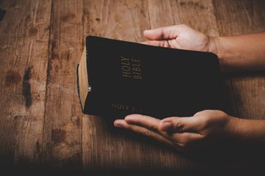 Close up of christian woman hand on holy bible are pray and worship for thank god in church with black background, adult female person are reading book, concept for faith, spirituality and religion