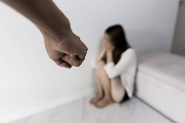 Man beating up his wife illustrating domestic violence. Fear and crying woman beats husband's abuse. sad and hopeless woman sitting in dark room concept of social problems.
