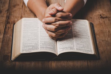 Close up of christian woman hand on holy bible are pray and worship for thank god in church with black background, adult female person are reading book, concept for faith, spirituality and religion