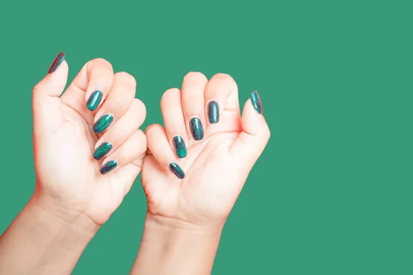 Female hand with green nail design on green background. Woman manicure is art beautiful summer style. Close-up of healthy young girl beauty fingers.