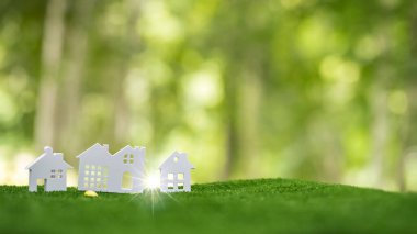 Environmentally eco-friendly real estate house. Small model building property home on grass in green nature ecology. Sustainable energy conservation residential design and sell - rent business concept