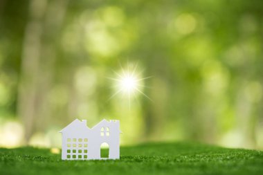 Environmentally eco-friendly real estate house. Small model building property home on grass in green nature ecology. Sustainable energy conservation residential design and sell - rent business concept
