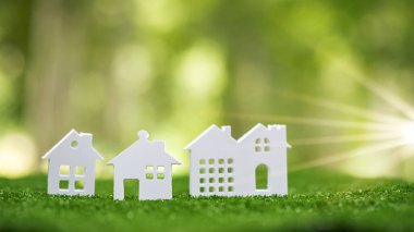 Environmentally eco-friendly real estate house. Small model building property home on grass in green nature ecology. Sustainable energy conservation residential design and sell - rent business concept