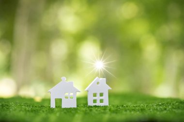 Environmentally eco-friendly real estate house. Small model building property home on grass in green nature ecology. Sustainable energy conservation residential design and sell - rent business concept