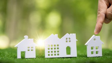 Environmentally eco-friendly real estate house. Small model building property home on grass in green nature ecology. Sustainable energy conservation residential design and sell - rent business concept