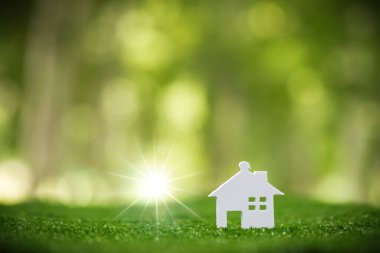 Environmentally eco-friendly real estate house. Small model building property home on grass in green nature ecology. Sustainable energy conservation residential design and sell - rent business concept