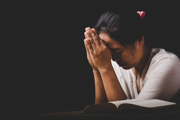 christian woman hand on holy bible are pray and worship for thank god in church with black background, adult female person are reading book, concept for faith, spirituality and religion