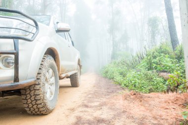Wheel truck closeup in countryside landscape with muddy road. Extreme adventure driving 4x4 vehicles for transport or travel or off-road races in outdoor nature. 4wd tire automobile on dirt mountain.