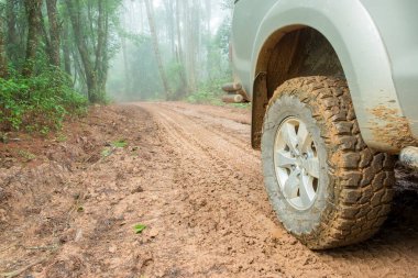 Wheel truck closeup in countryside landscape with muddy road. Extreme adventure driving 4x4 vehicles for transport or travel or off-road races in outdoor nature. 4wd tire automobile on dirt mountain.