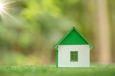 Environmentally eco-friendly real estate house. Small model building property home on grass in green nature ecology. Sustainable energy conservation residential design and sell - rent business concept