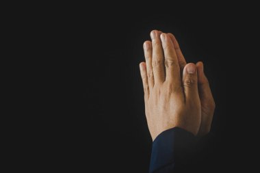 Hand folded prayer to god on dark in church concept for faith, spirituality and religion, woman person praying on holy bible in morning. Christian catholic woman hand with worship in black background.