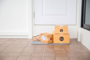 Cardboard parcel box near door on floor. Online shopping, boxes delivered to your front door. Easy to steal when nobody is home. Parcel in cardboard box on doorstep. Delivery service