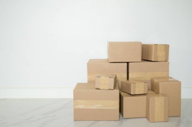 Stack of cardboard boxes for moving, Empty room with a white wall and cardboard boxes with unbranded barcode on the floor. Delivery of goods, shopping. Cardboard boxes on gray wall background.