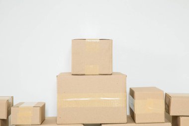 Stack of cardboard boxes for moving, Empty room with a white wall and cardboard boxes with unbranded barcode on the floor. Delivery of goods, shopping. Cardboard boxes on gray wall background.