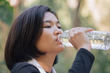 One asian beautiful woman drinking water on camping camp in summer at nature forest