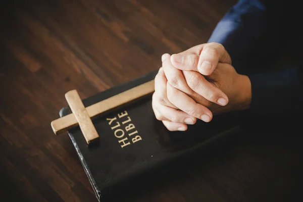 Hand folded in prayer to god on Holy Bible book in church concept for faith, spirituality and religion, woman person praying on holy bible in morning. christian catholic woman hand with Bible worship.