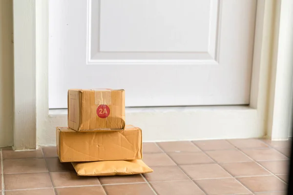 Cardboard parcel box near door on floor. Online shopping, boxes delivered to your front door. Easy to steal when nobody is home. Parcel in cardboard box on doorstep. Delivery service