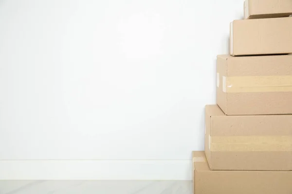 Stack of cardboard boxes for moving, Empty room with a white wall and cardboard boxes with unbranded barcode on the floor. Delivery of goods, shopping. Cardboard boxes on gray wall background.