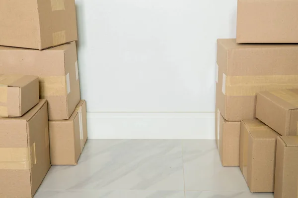 Stack of cardboard boxes for moving, Empty room with a white wall and cardboard boxes with unbranded barcode on the floor. Delivery of goods, shopping. Cardboard boxes on gray wall background.