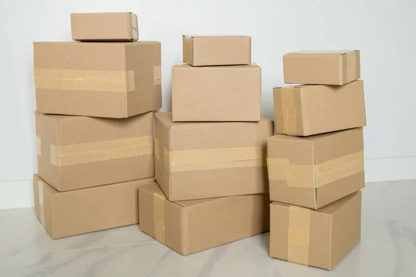 Stack of cardboard boxes for moving, Empty room with a white wall and cardboard boxes with unbranded barcode on the floor. Delivery of goods, shopping. Cardboard boxes on gray wall background.