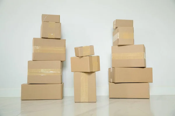 Stack of cardboard boxes for moving, Empty room with a white wall and cardboard boxes with unbranded barcode on the floor. Delivery of goods, shopping. Cardboard boxes on gray wall background.