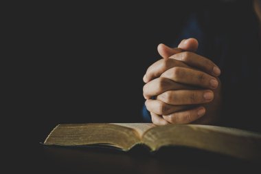 Hand folded in prayer to god on Holy Bible book in church concept for faith, spirituality and religion, woman person praying on holy bible in morning. christian catholic woman hand with Bible worship.