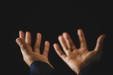 Hand folded prayer to god on dark in church concept for faith, spirituality and religion, woman person praying on holy bible in morning. Christian catholic woman hand with worship in black background.