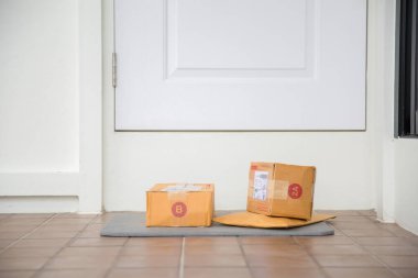 Cardboard parcel box near door on floor. Online shopping, boxes delivered to your front door. Easy to steal when nobody is home. Parcel in cardboard box on doorstep. Delivery service