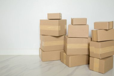 Stack of cardboard boxes for moving, Empty room with a white wall and cardboard boxes with unbranded barcode on the floor. Delivery of goods, shopping. Cardboard boxes on gray wall background.