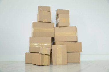 Stack of cardboard boxes for moving, Empty room with a white wall and cardboard boxes with unbranded barcode on the floor. Delivery of goods, shopping. Cardboard boxes on gray wall background.