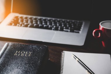 Siyah ahşap arka planda eğitim için kâğıt içeren kutsal İncil kitabı. Protestan inancı olan Hıristiyan Katolik kilisede dua ediyor. İnanç, Tanrı ve din hakkında bilgi edinme kavramı..