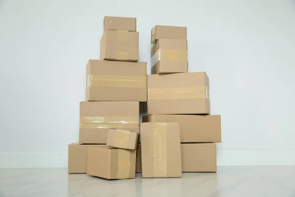 Stack of cardboard boxes for moving, Empty room with a white wall and cardboard boxes with unbranded barcode on the floor. Delivery of goods, shopping. Cardboard boxes on gray wall background.