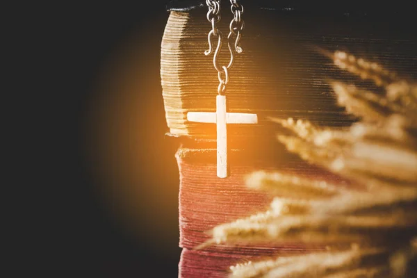 Holy bible book with cross or crucifix on old black wooden background. Christian catholic with protestant pray and study in church. Concept of cognition about faith god and religion, jesus spiritual.