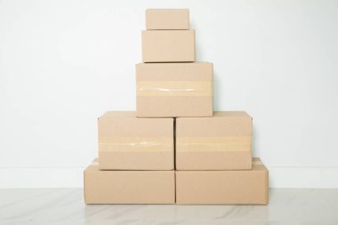 Stack of cardboard boxes for moving, Empty room with a white wall and cardboard boxes with unbranded barcode on the floor. Delivery of goods, shopping. Cardboard boxes on gray wall background.