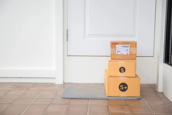 Cardboard parcel box near door on floor. Online shopping, boxes delivered to your front door. Easy to steal when nobody is home. Parcel in cardboard box on doorstep. Delivery service