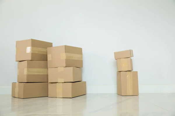 Stack of cardboard boxes for moving, Empty room with a white wall and cardboard boxes with unbranded barcode on the floor. Delivery of goods, shopping. Cardboard boxes on gray wall background.