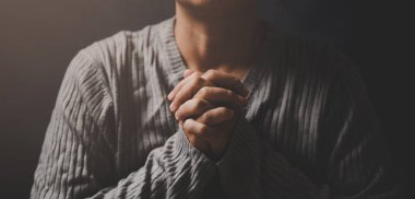 İsa dini ve Hıristiyanlık ibadeti ya da dua kavramı. Hıristiyan katolik kadın kilisede karanlıkta Tanrı 'ya dua ediyor. Dua eden kişi siyah arka planda. Kız İsa 'ya inanıyor ve inanıyor..