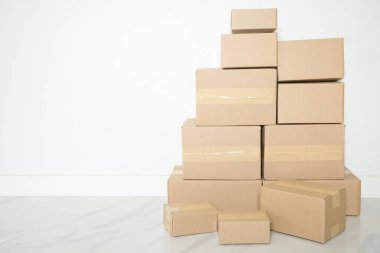 Stack of cardboard boxes for moving, Empty room with a white wall and cardboard boxes with unbranded barcode on the floor. Delivery of goods, shopping. Cardboard boxes on gray wall background.
