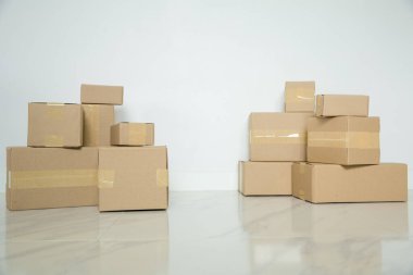Stack of cardboard boxes for moving, Empty room with a white wall and cardboard boxes with unbranded barcode on the floor. Delivery of goods, shopping. Cardboard boxes on gray wall background.