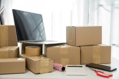 KOBİ 'nin internet işleri, teslimat bilgisayarları, barkodlar, kutular, hisse senetleri ve karton paketlerdeki ürünleri kontrol etmek için gerekli malzemeler. Ev ofisinde çalışan küçük bir işletme. teslimat hizmeti ürünü evde.