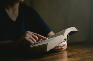 Dua eden kişi siyah arka planda. Hıristiyan katolik kadın kilisede karanlıkta Tanrı 'ya dua ediyor. Kız İsa 'ya inanıyor ve inanıyor. İsa dini ve Hıristiyanlık ibadeti veya dua kavramı.